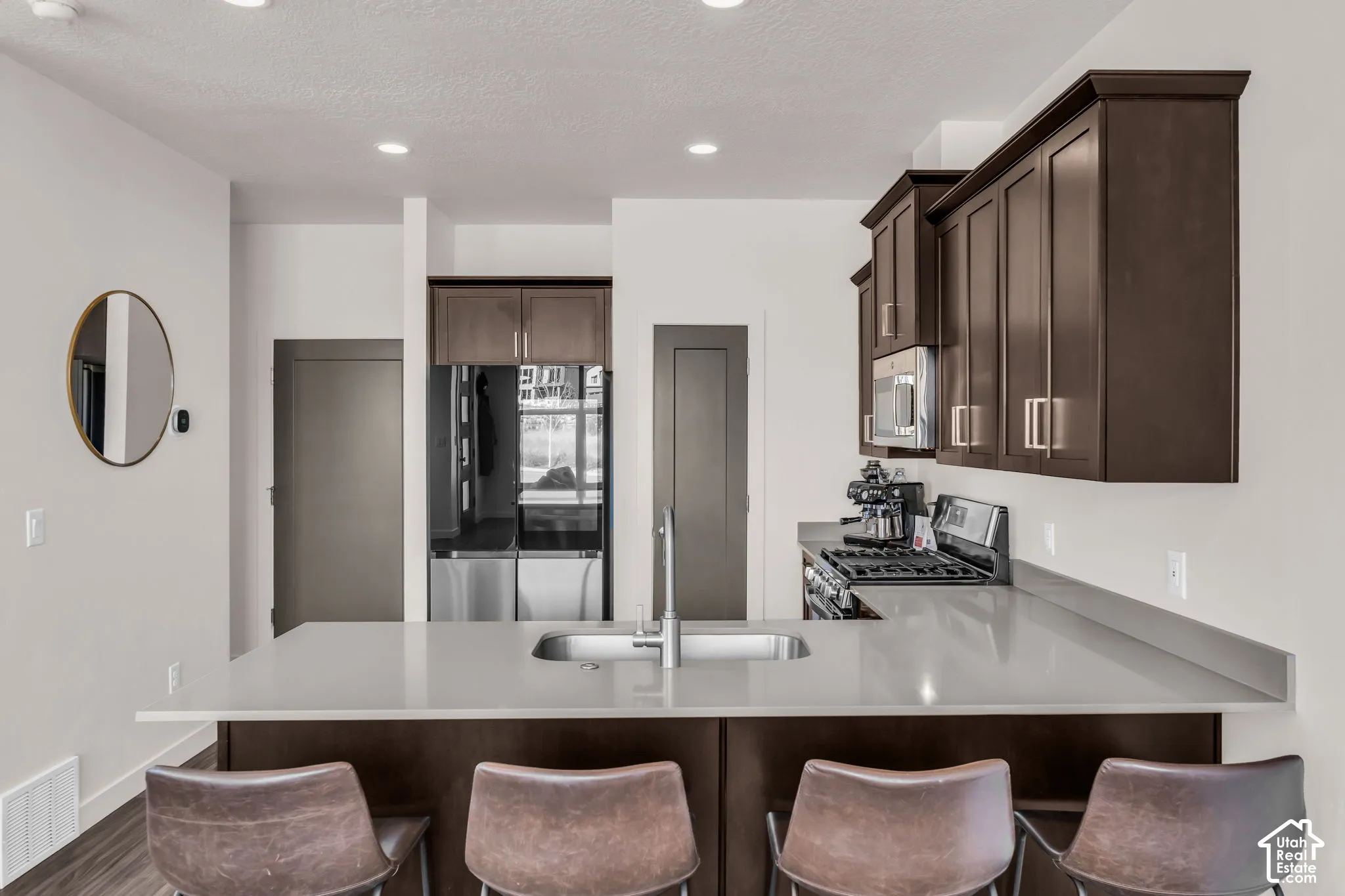 Kitchen featuring dark wood cabinetry, solid-surface countertops, recessed lighting, and stainless steel appliances