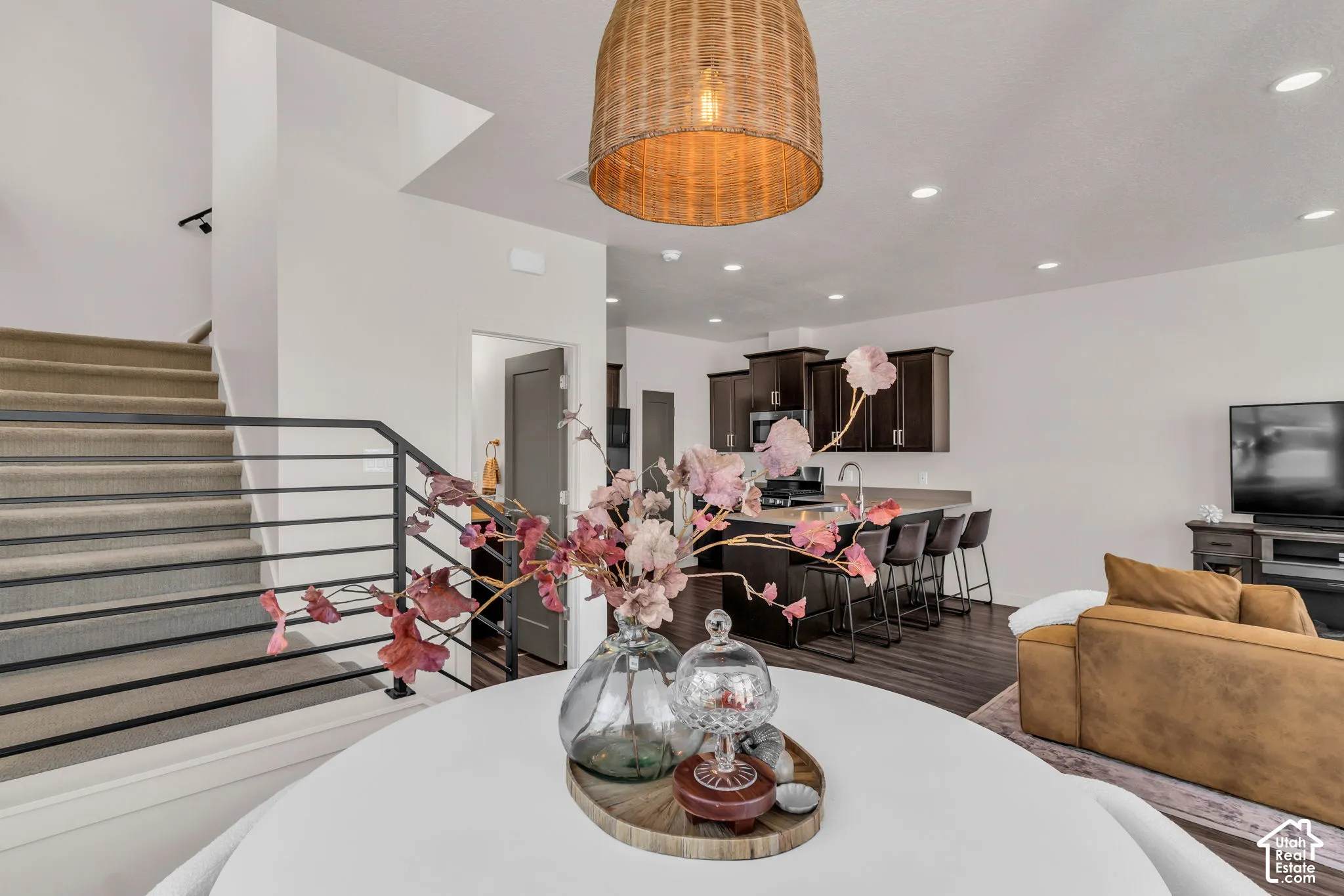 Staircase featuring dark metal horizontal railings, woven pendant lighting, recessed ceiling lights, and wood-finish flooring