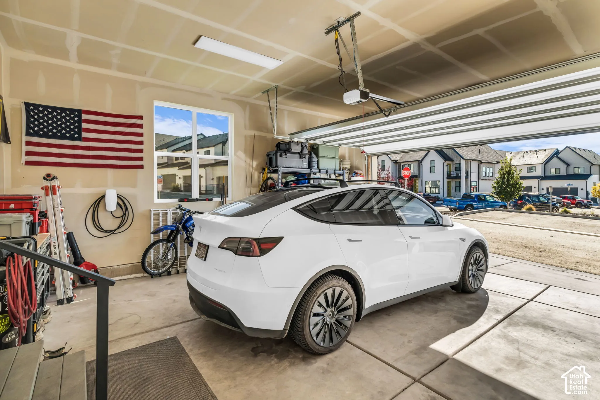 Attached multi-car garage featuring a dedicated electric vehicle charging station, concrete flooring, overhead LED lighting, and an operable window