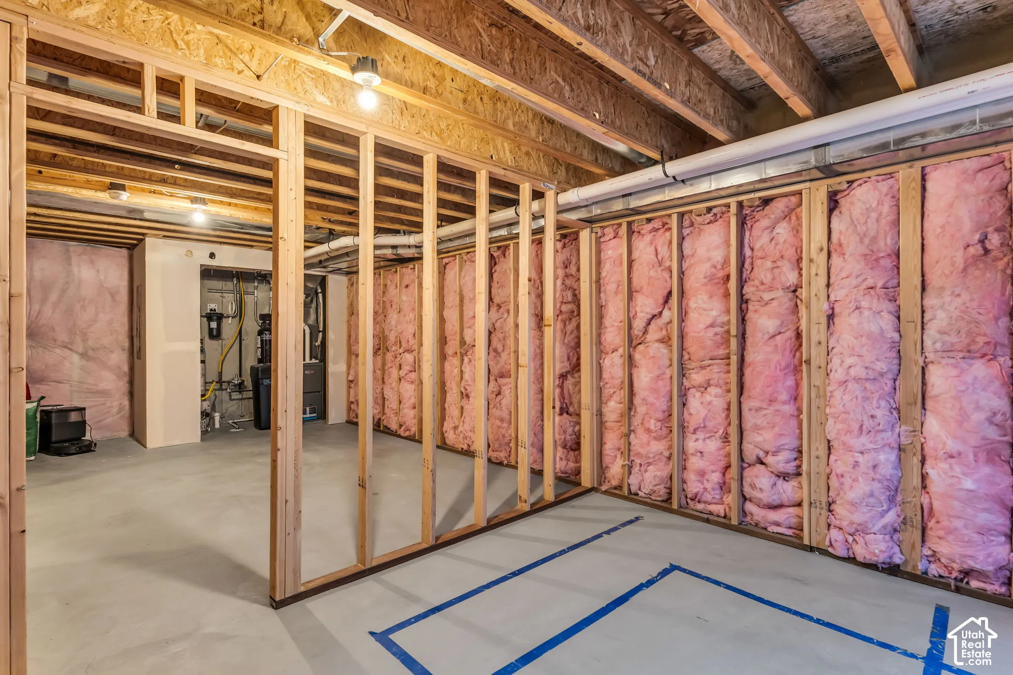 Unfinished lower level featuring exposed wood-stud framing, fiberglass batt insulation, concrete flooring, and exposed floor joists