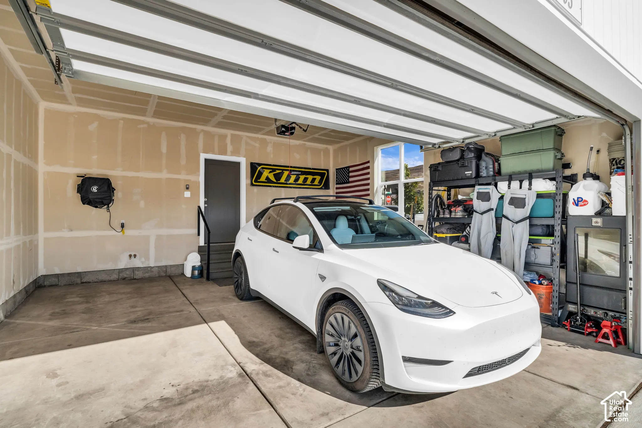Attached garage featuring concrete flooring, an automated overhead door, and a dedicated service door with handrail