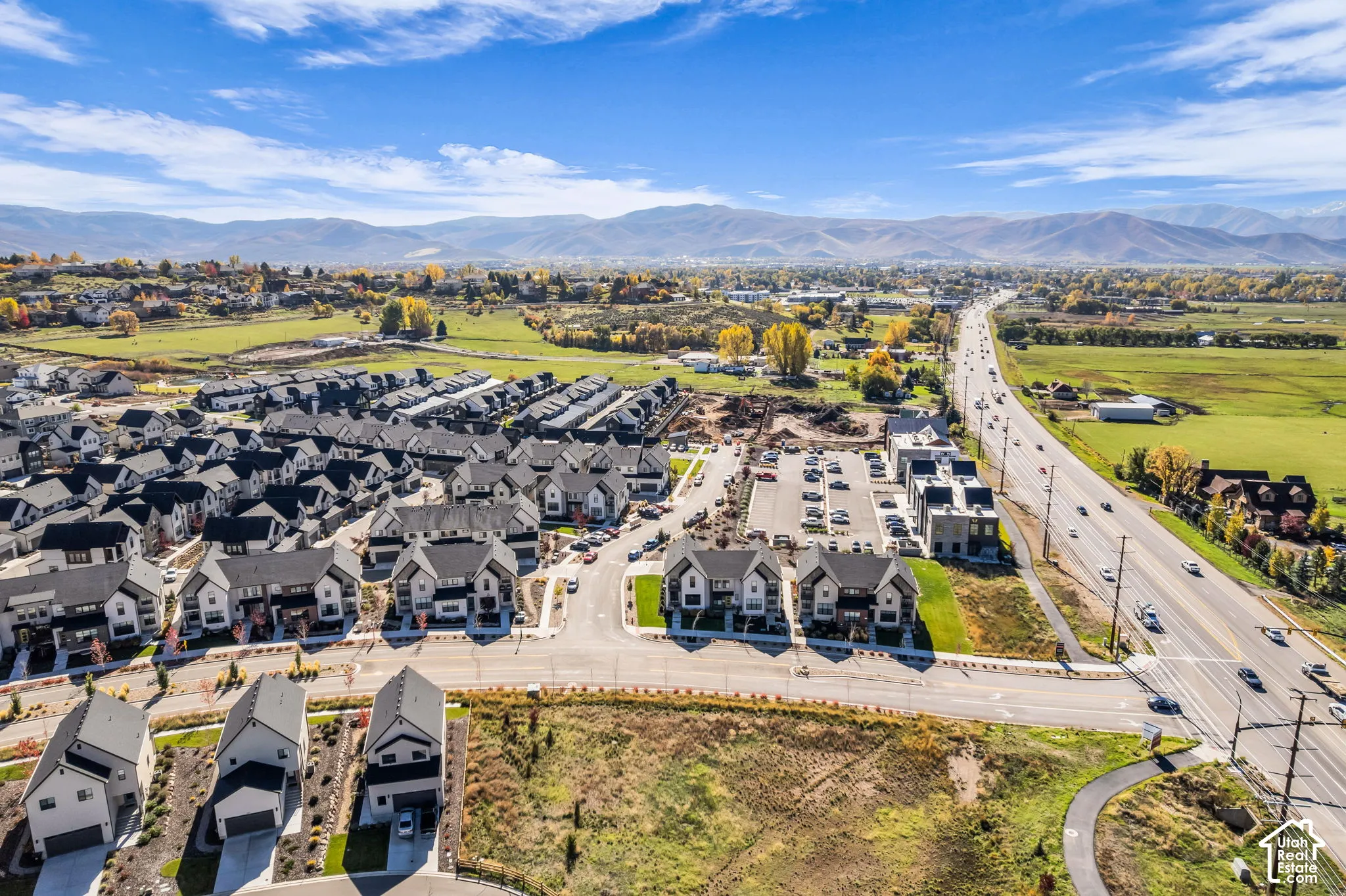 Aerial perspective of a multi-family residential community featuring asphalt-shingled gable roofs, paved access roads, and mountain scenery