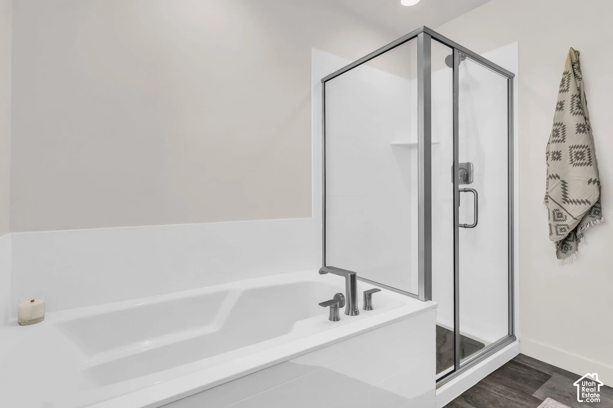 Deep soaking tub, separate shower enclosure with a metallic frame, integrated shower and tub surround, and widespread metal faucet fixtures
