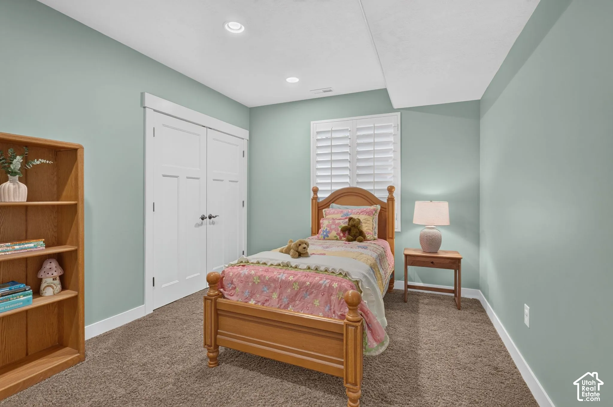 Neutral-toned walls paired with plush carpeting, white double-door closet, recessed ceiling lighting, and plantation-style window shutters