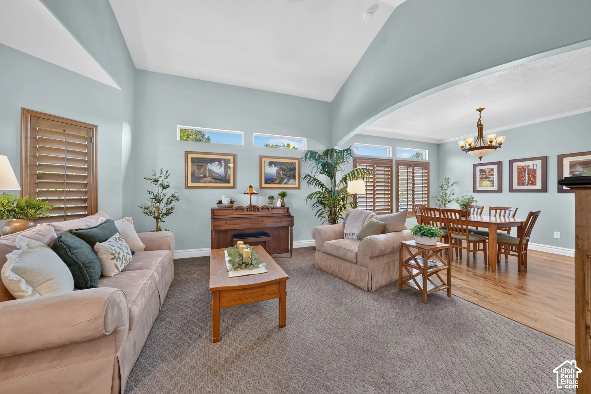 Vaulted ceilings, transom windows, wood-finish plantation shutters, and a multi-tiered chandelier