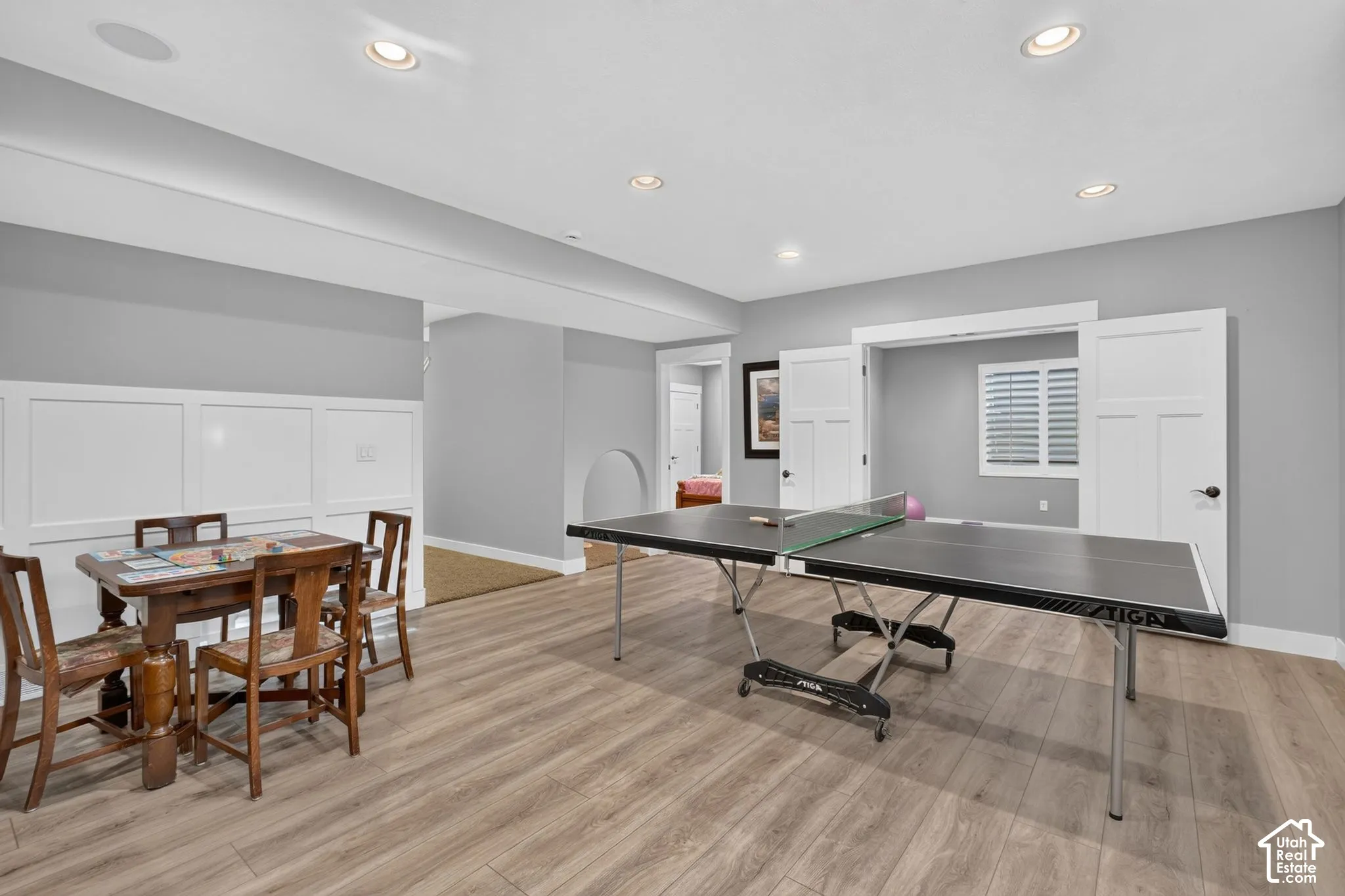 Recessed lighting, wood-finish flooring, white wainscoting, and interior double doors with shutters