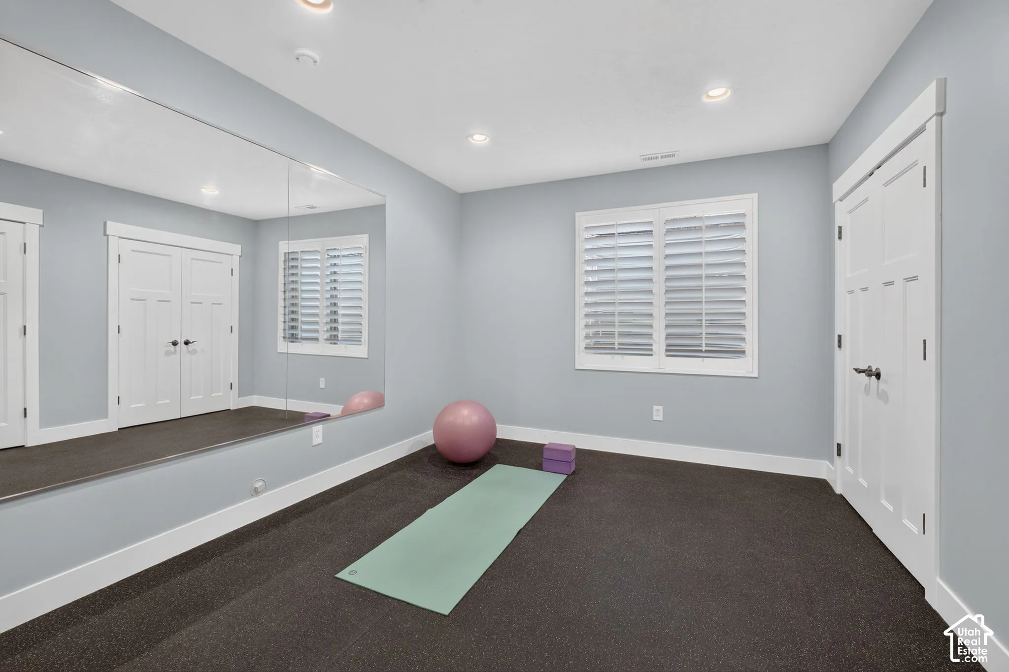 Interior room featuring wall-to-wall mirror, recessed lighting, carpeted flooring, double-panel interior doors, and shutters