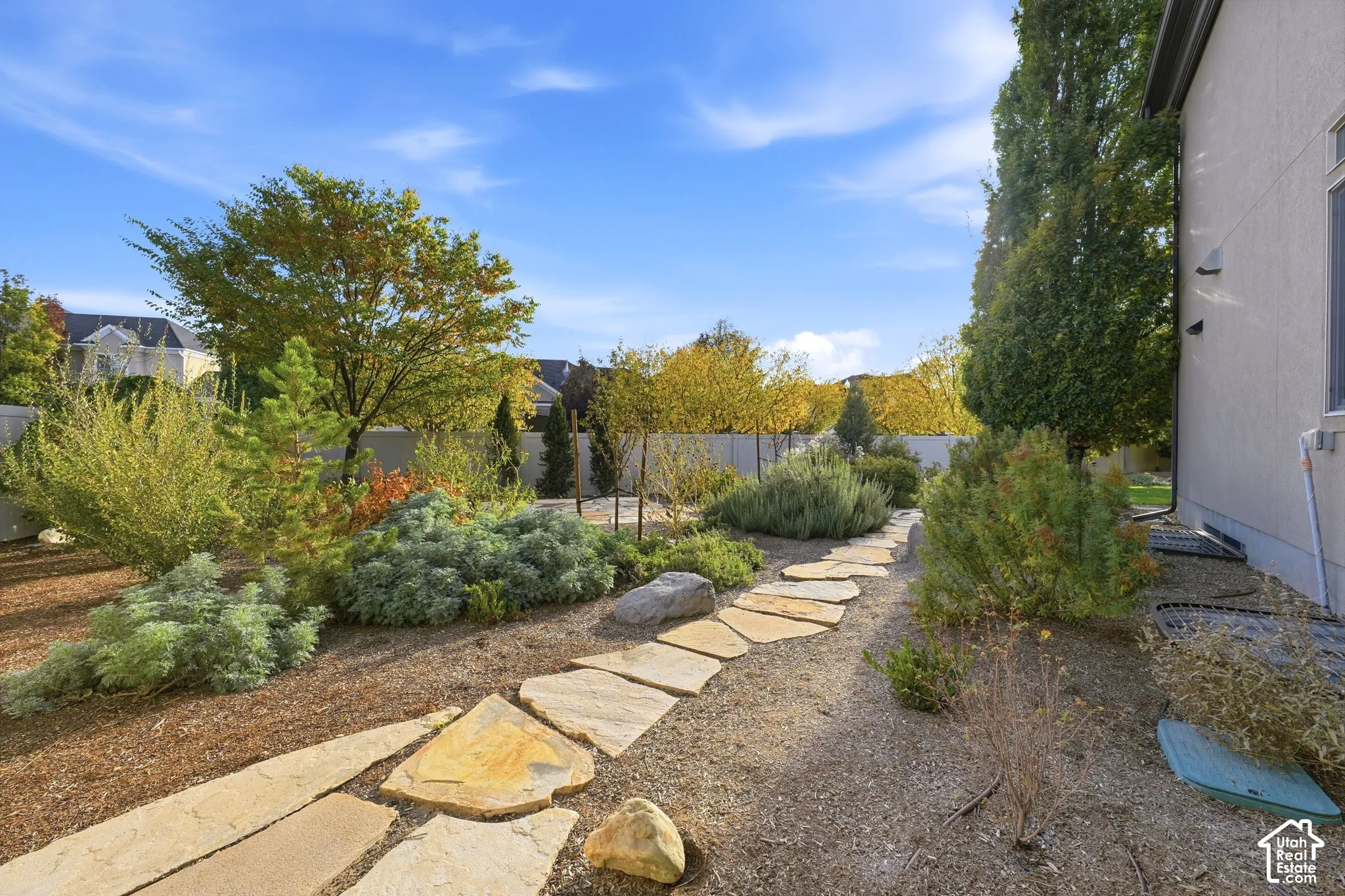 Landscaped side yard featuring natural stone pavers, mulch ground cover, mature shrubs, and decorative boulder accents