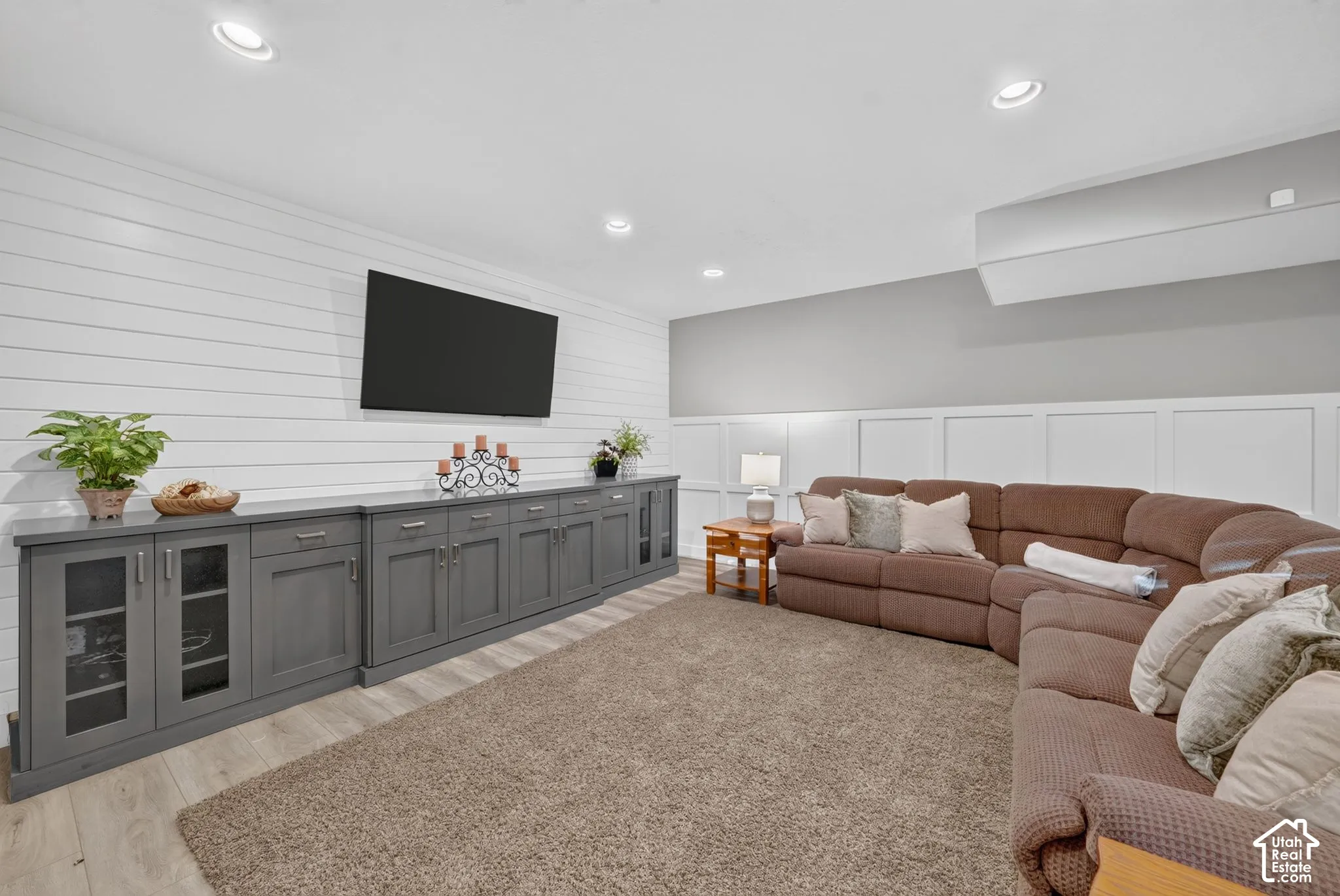 Horizontal shiplap accent wall, custom built-in charcoal cabinetry, recessed lighting, and white wainscoting