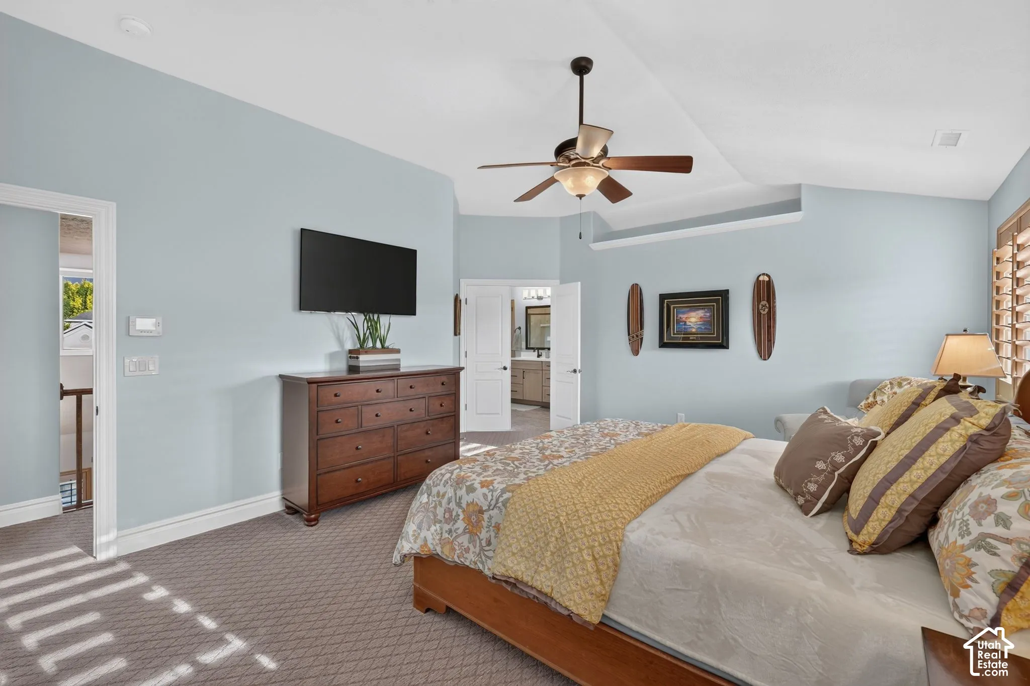 Vaulted ceiling with a central multi-blade ceiling fan, neutral wall-to-wall carpeting, and shutter-style window coverings