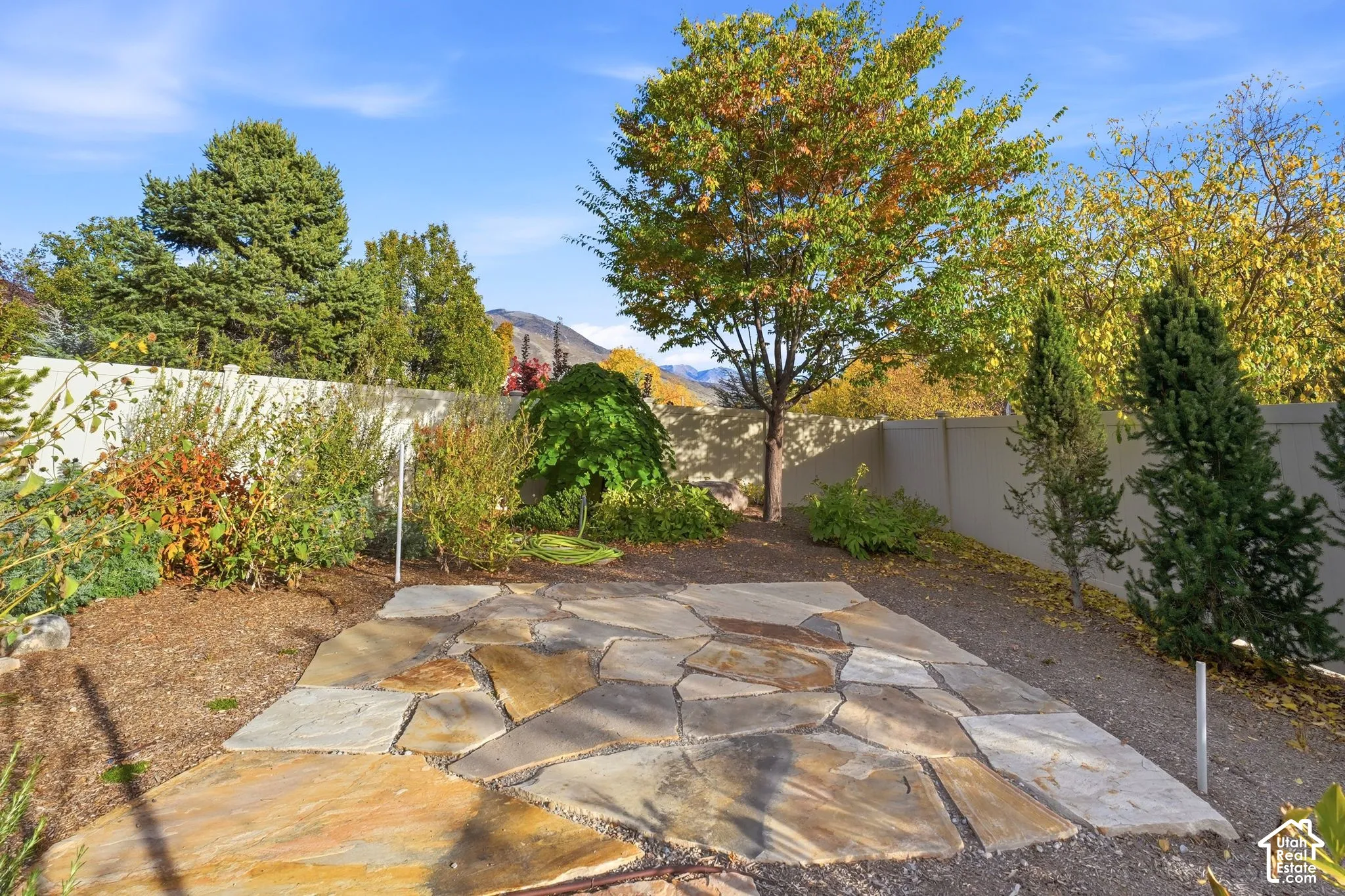 Flagstone patio featuring mature trees, shrubs, and perimeter privacy fencing