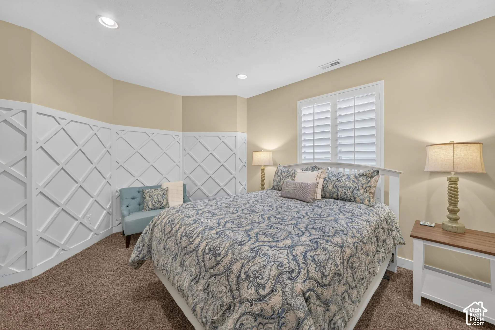 Room featuring custom white lattice-pattern wall molding, neutral carpeting, recessed ceiling lighting, and interior shutters