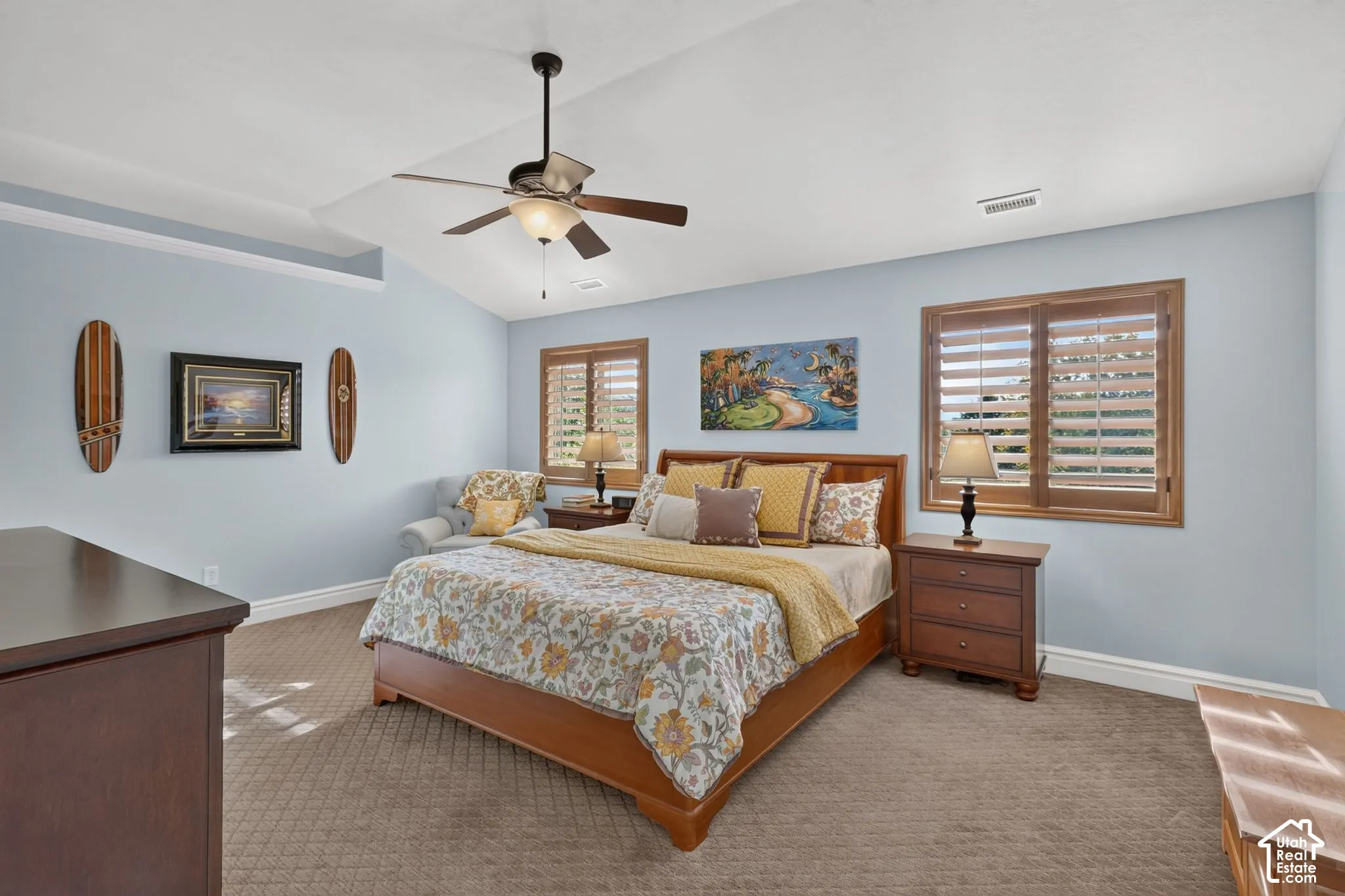 Vaulted ceiling with a centrally mounted ceiling fan, carpeting, and multiple windows featuring wooden plantation shutters