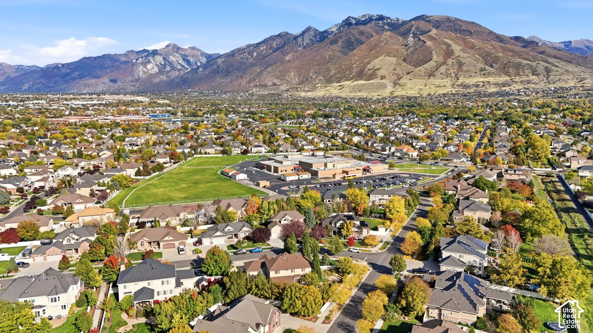 Aerial perspective of the residential community featuring mature trees, paved roadways, and prominent mountain backdrops