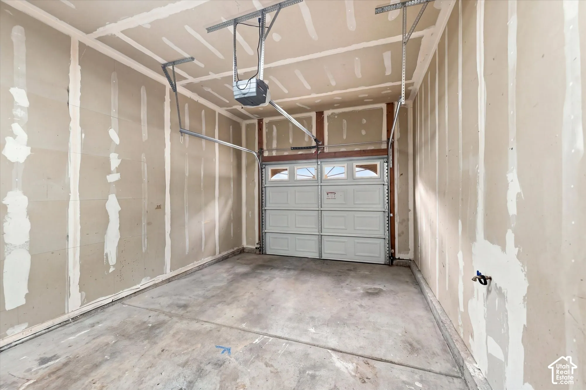 Garage featuring unfinished drywall, a concrete floor, an overhead door with integrated windows, and an automated garage door opener