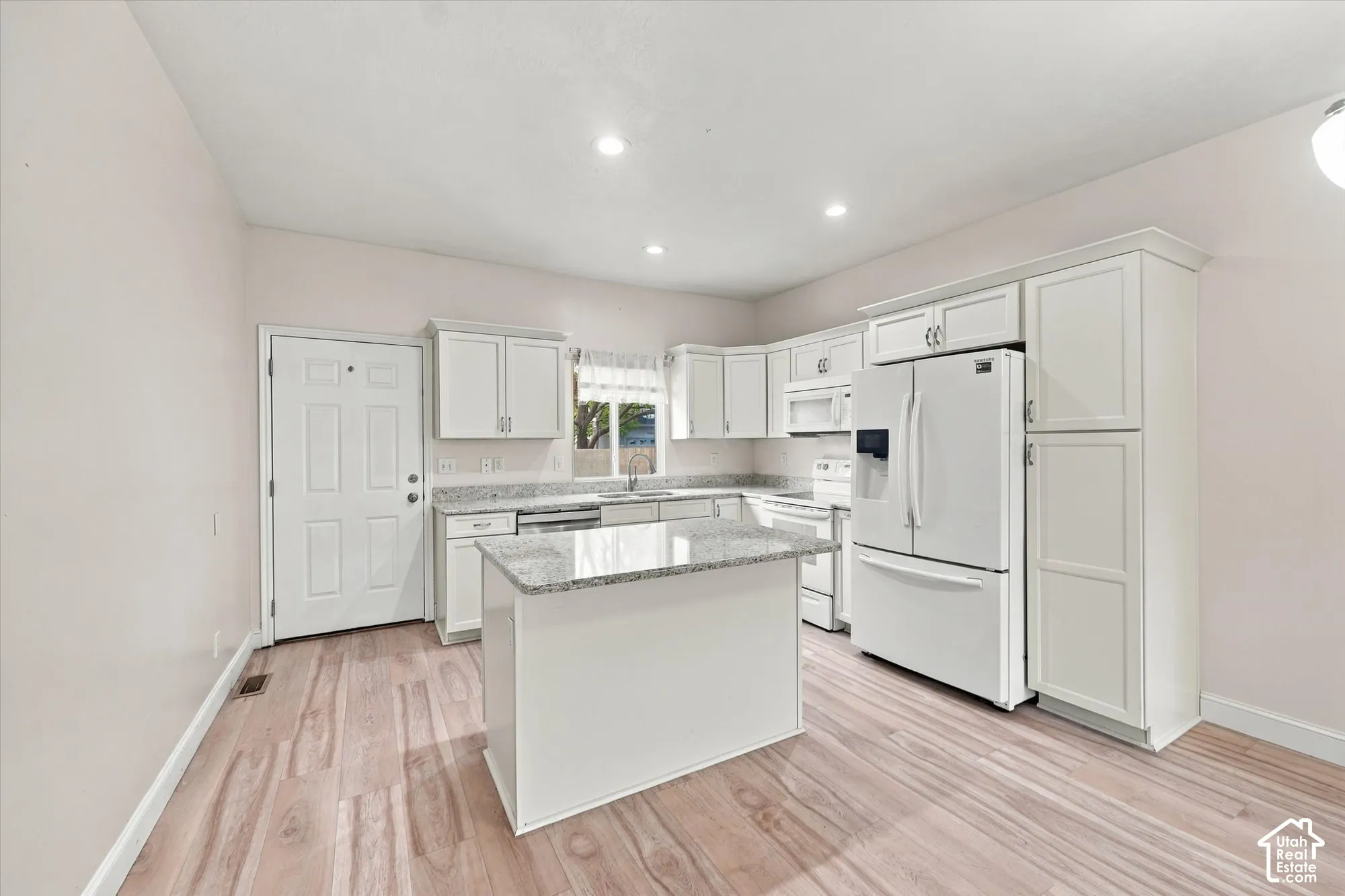 Kitchen featuring white cabinetry, stone-surface countertops, center island, recessed lighting, and wood-finish flooring