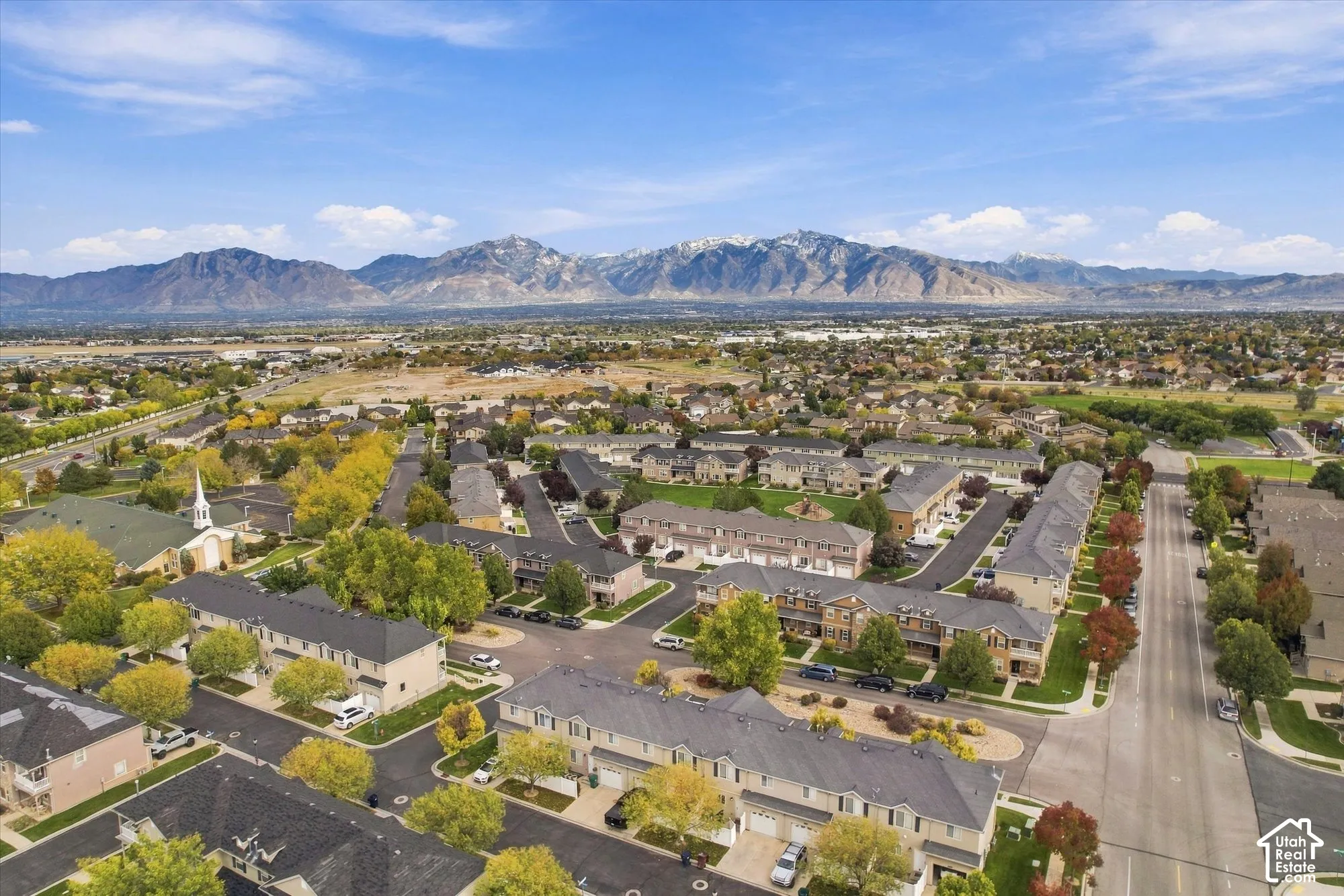Aerial perspective featuring multi-story residential structures with pitched rooflines, paved street networks, and a backdrop of mountain ranges