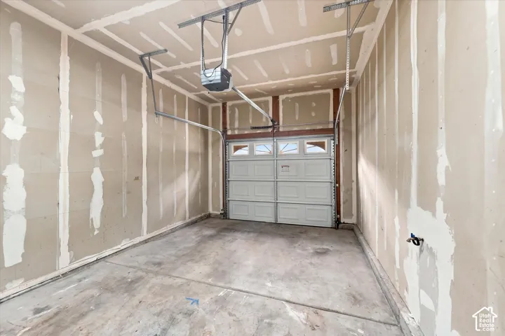 Garage featuring unfinished drywall, a concrete floor, an overhead door with integrated windows, and an automated garage door opener