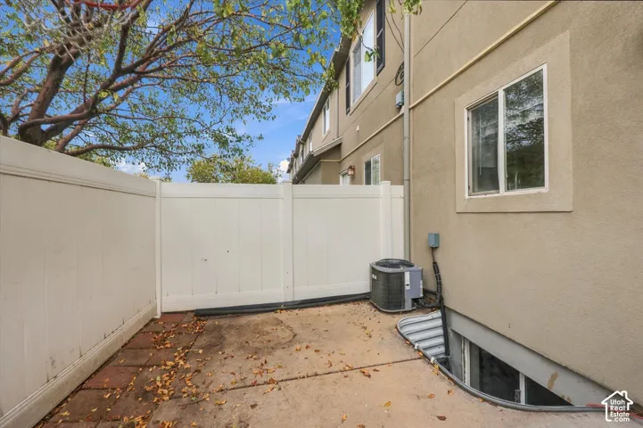 Exterior patio featuring a concrete surface, bordered by a white privacy fence and a window well egress