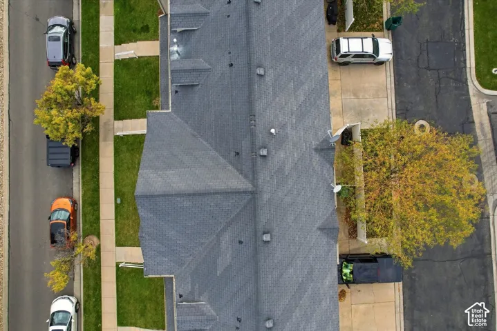 Aerial view featuring a multi-gabled asphalt shingle roof and dedicated concrete driveway