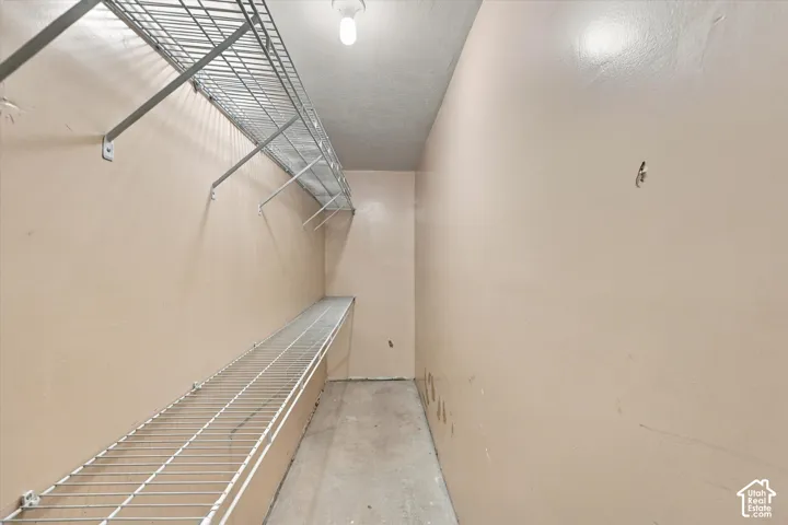 Storage space featuring dual-level white wire shelving and a ceiling-mounted light fixture