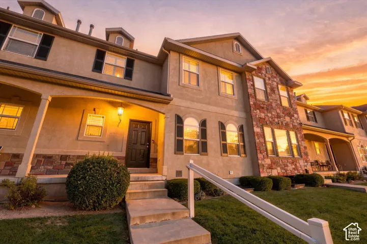 Multi-level exterior featuring stucco siding, stone veneer accents, arched windows, and a covered front porch