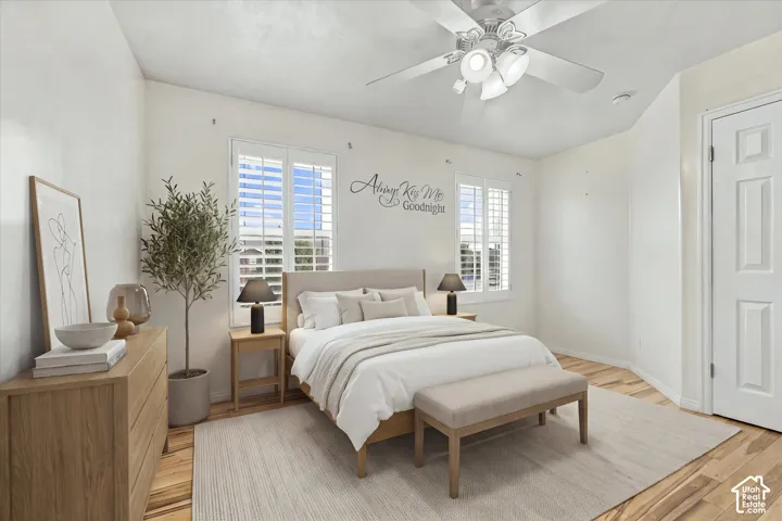 Bedroom featuring wood-finish flooring, plantation shutters, and a central ceiling fan with integrated lighting
