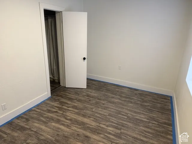 Interior room featuring wood-finish flooring, white walls, and a white swing door with a round black knob