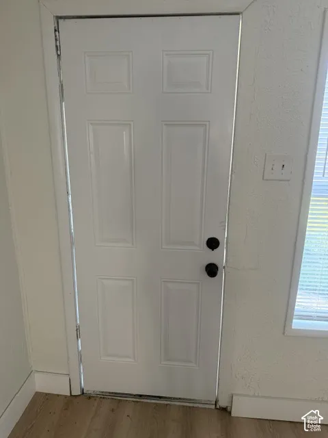 Six-panel white door with matte black hardware and wood-finish flooring