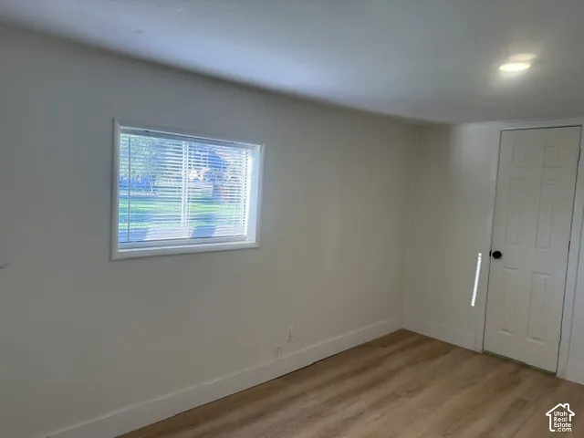 Neutral-toned interior featuring wood-finish flooring, a recessed lighting fixture, and a six-panel door with black hardware