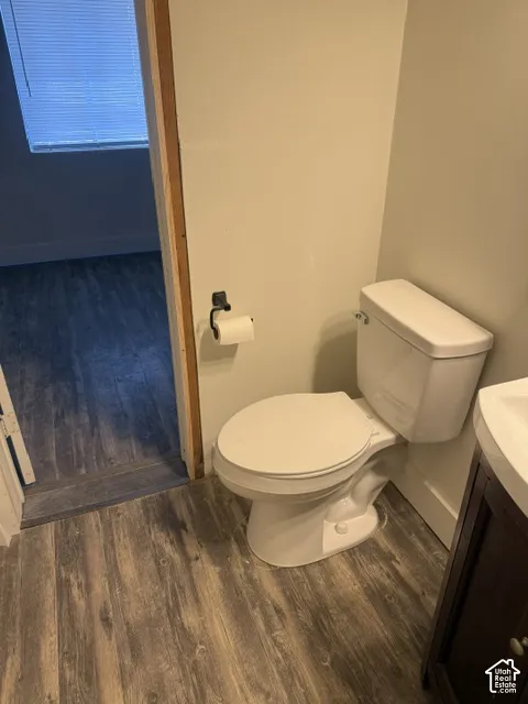 Restroom featuring wood-finish flooring, a porcelain toilet, and a matte black toilet paper holder