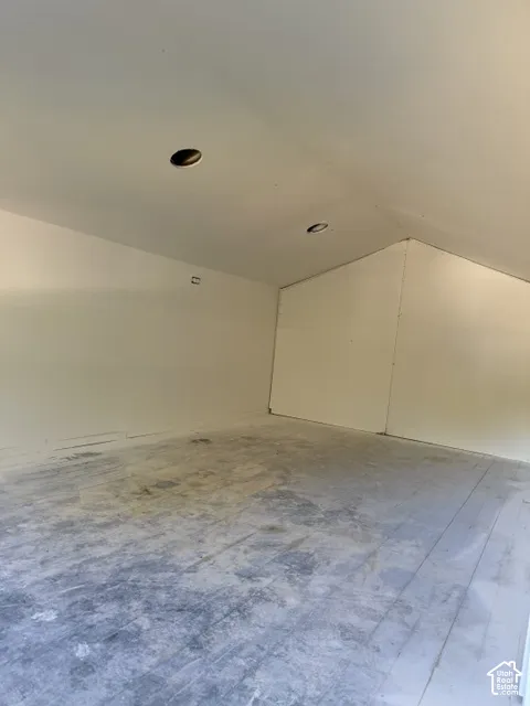 Vaulted ceiling space featuring neutral wall finishes and recessed lighting
