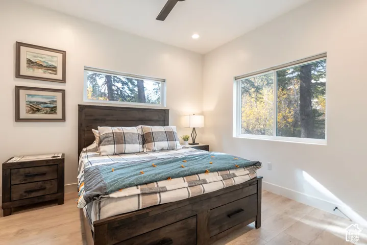 Room featuring wood-finish flooring, recessed lighting, a ceiling fan, and large windows providing natural light