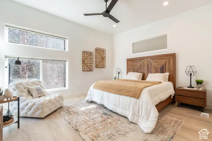 High ceilings featuring a matte black finish ceiling fan, wood-finish flooring, and multiple horizontal windows