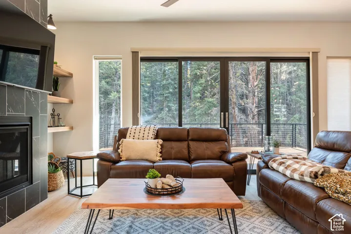Living area featuring a floor-to-ceiling tile-surround fireplace, built-in wooden shelving, wood-finish flooring, and multi-panel sliding glass doors