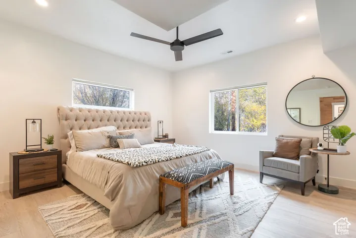 Room featuring a tray ceiling, matte black ceiling fan, wood-finish flooring, and recessed lighting