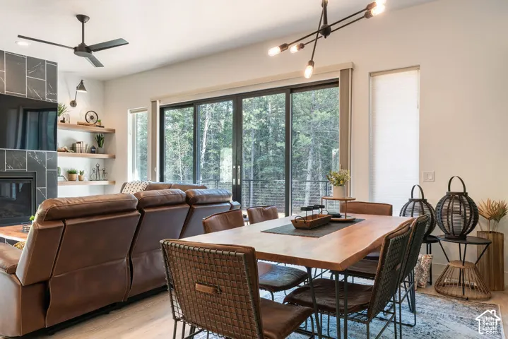 Large multi-panel sliding glass door, floor-to-ceiling stone-tiled fireplace surround, integrated wall shelving, industrial-style multi-arm chandelier, and ceiling fan with matte finish