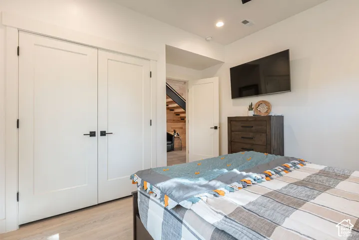 Double-door closet with shaker-style panels, matte black hardware, recessed lighting, and wood-finish flooring