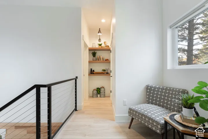 Stairway featuring a metal cable railing, light wood-finish flooring, built-in wooden shelving, and recessed lighting