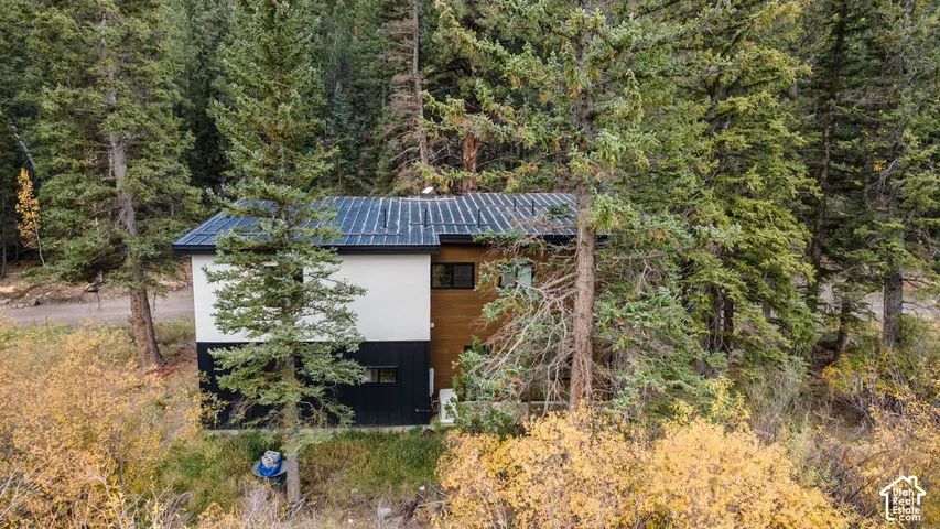 Modern exterior featuring a metal roof, smooth white siding, horizontal wood-tone paneling, and black vertical metal siding