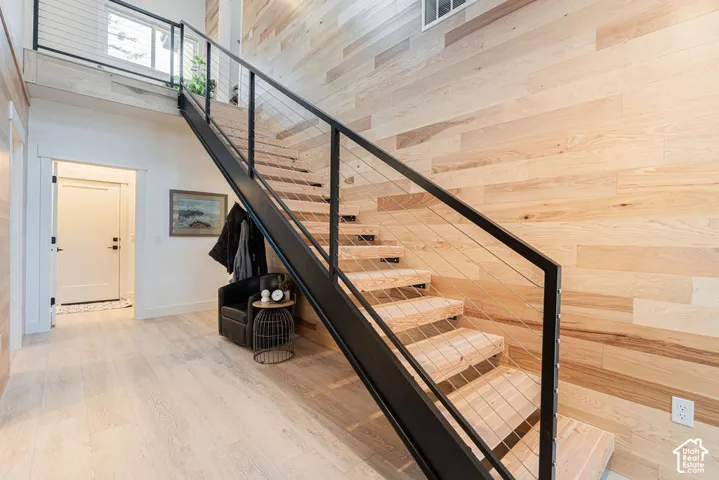 Floating staircase featuring wood treads, black metal stringers, and a cable railing system set against a full-height wood-paneled accent wall