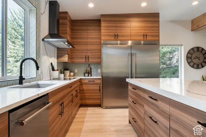 Kitchen featuring flat-panel wood-finish cabinetry, white countertops, stainless steel appliances, a herringbone tile backsplash, and a matte black gooseneck faucet