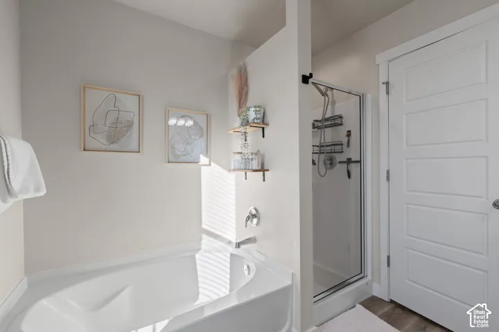 Deep soaking tub with chrome faucet fixtures, separate shower enclosure with a glass door, and four-panel interior door