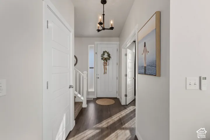 Foyer featuring wood-finish flooring, a contemporary three-light chandelier, a solid-core front door with a vertical glass sidelight, and white paneled interior doors