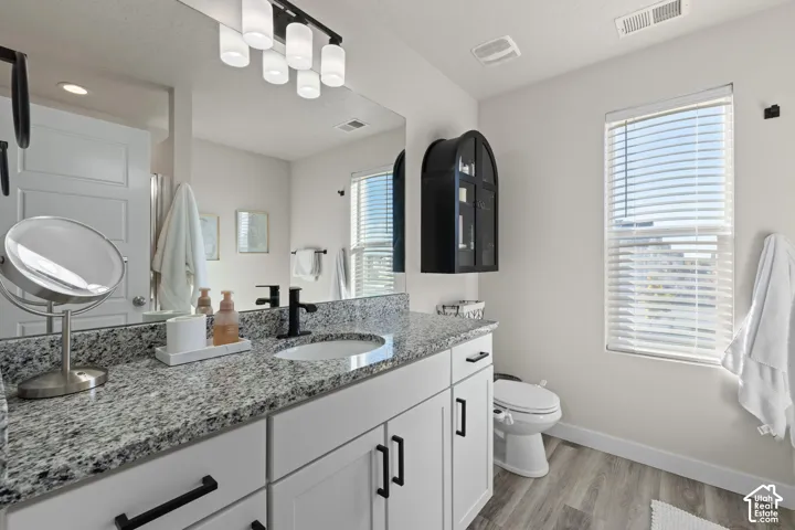 Bathroom featuring a white shaker-style vanity with stone-pattern countertop, integrated oval sink, matte black hardware, and an oversized vanity mirror