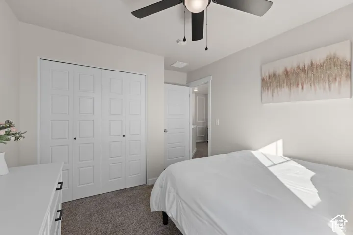 Neutral-toned room featuring a ceiling fan with integrated lighting, wall-to-wall carpeting, and floor-to-ceiling bifold closet doors