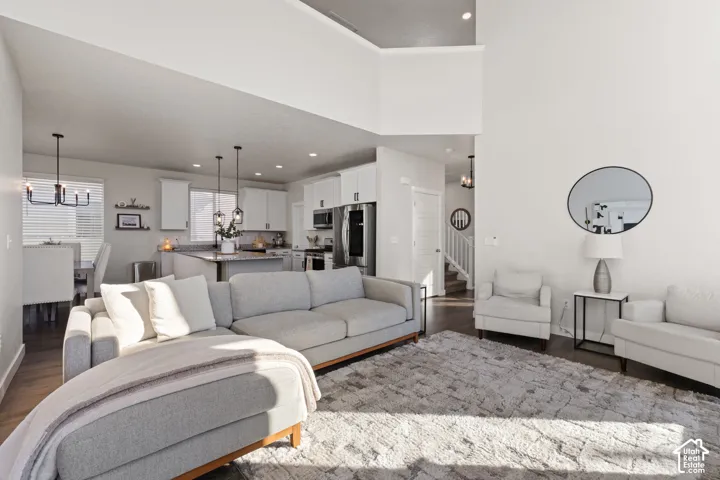 Vaulted ceilings, open-concept floor plan, kitchen island with stone-surface countertop, dark wood-finish flooring, and recessed lighting