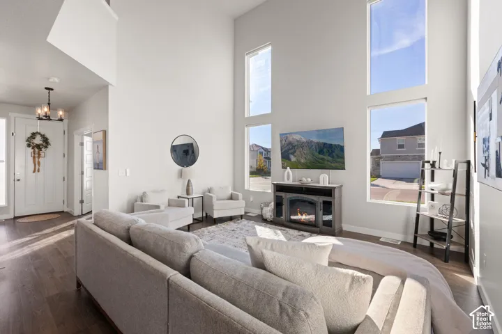 Great room featuring vaulted ceilings, floor-to-ceiling windows, wood-finish flooring, and a multi-light chandelier