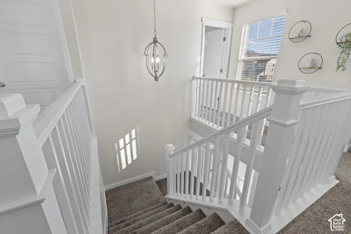 Staircase featuring white balusters with square newel posts, carpeted treads, and an orb-style pendant light fixture