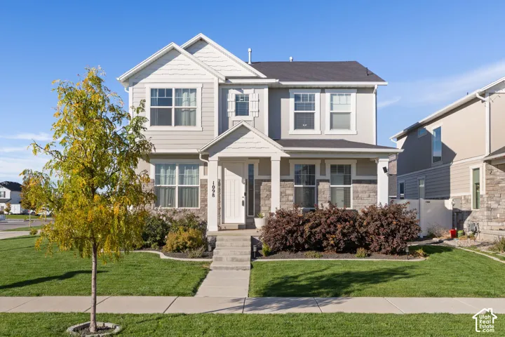 Two-story exterior featuring horizontal lap siding, stone veneer accents, a covered front porch with a gabled roofline, and multi-pane windows